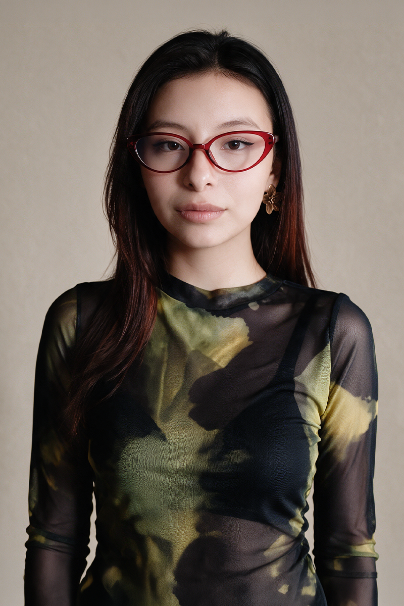 Ximena con gafas rojas y blusa de estampado verde y negro