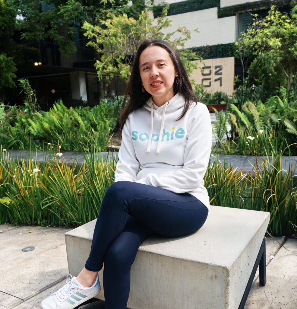 Mujer sonriente con buzo blanco de Sophie sentada en un jardín
